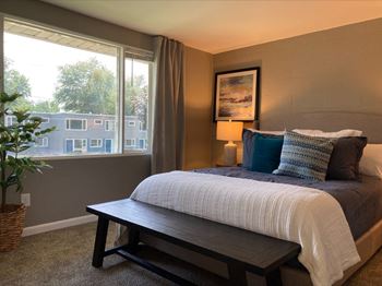 A bedroom with a bed, a bench, and a window